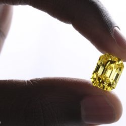 coloured diamond yellow diamond, emerald cut held between two fingers